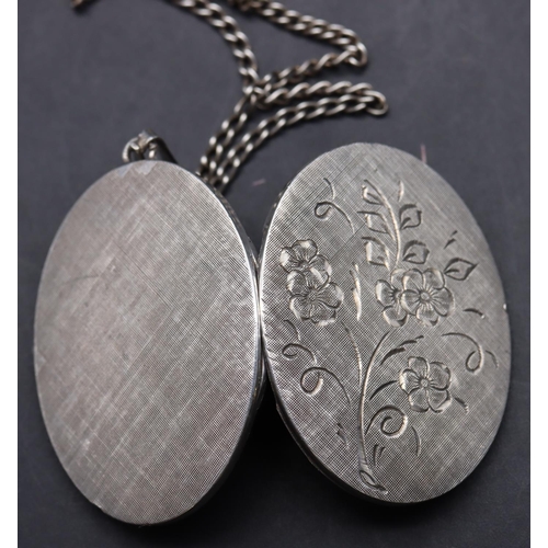 417 - A silver oval locket with engraved floral hinged front, with chain, 19.5 grams