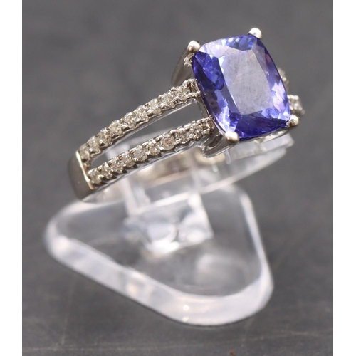 443 - An 18ct white gold ladies' dress ring set with centre tanzanite flanked by diamonds to open shoulder... 