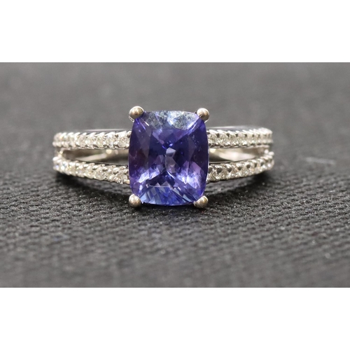 443 - An 18ct white gold ladies' dress ring set with centre tanzanite flanked by diamonds to open shoulder... 