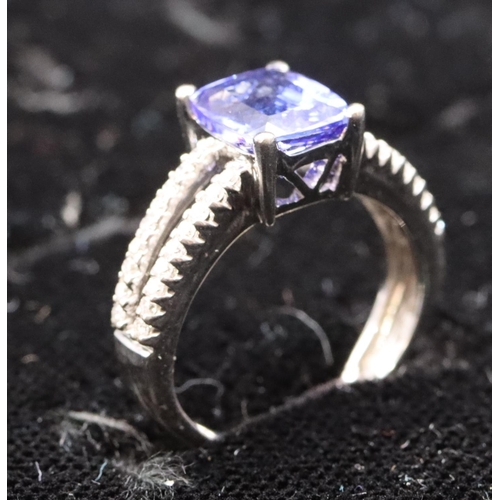 443 - An 18ct white gold ladies' dress ring set with centre tanzanite flanked by diamonds to open shoulder... 