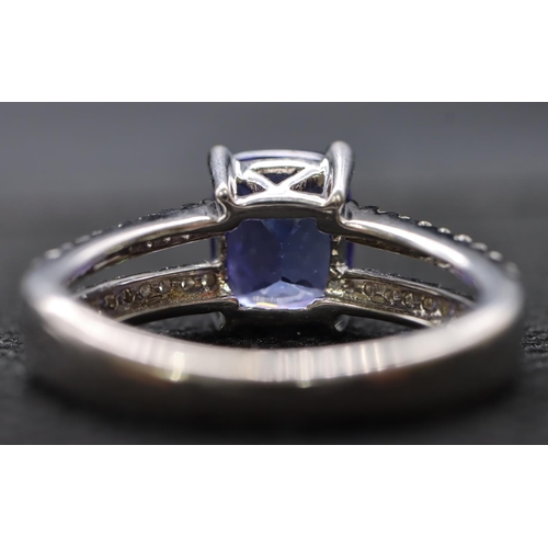 443 - An 18ct white gold ladies' dress ring set with centre tanzanite flanked by diamonds to open shoulder... 