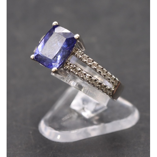 443 - An 18ct white gold ladies' dress ring set with centre tanzanite flanked by diamonds to open shoulder... 