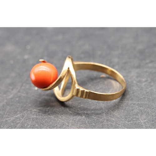 489 - A Continental gold ladies' ring set with coral, with open shoulders, size O/P, 3.5 grams gross