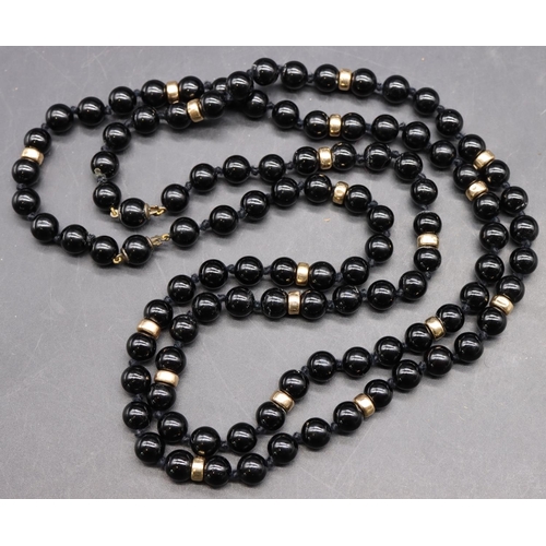 496 - A Long black bead necklace mounted with small gold beads, 102cm long