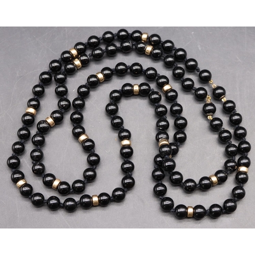 496 - A Long black bead necklace mounted with small gold beads, 102cm long