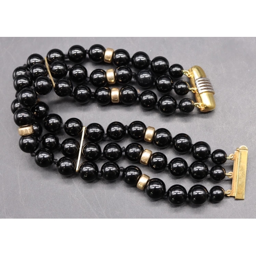 497 - A 14ct gold and triple row black bead bracelet, mounted with further gold beads, 19cm long