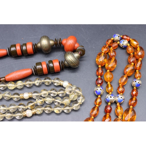 501 - An amber bead necklace with chamfer decoration interspersed with small silver and blue enamelled bal... 