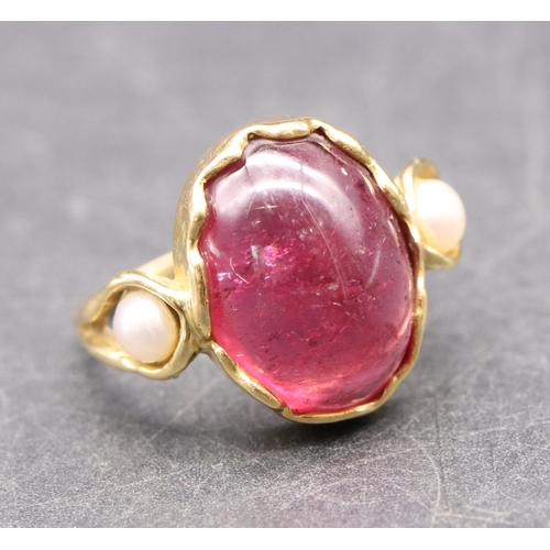 550 - An 18ct gold ladies' ring set with red cabochon flanked by 2 half pearls, size R, 5.3 grams gross