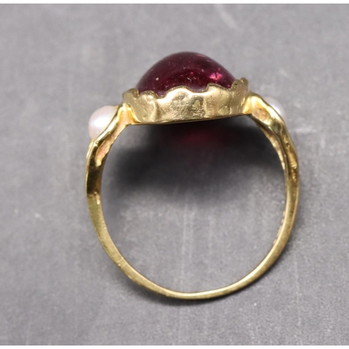 550 - An 18ct gold ladies' ring set with red cabochon flanked by 2 half pearls, size R, 5.3 grams gross