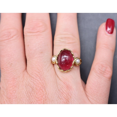 550 - An 18ct gold ladies' ring set with red cabochon flanked by 2 half pearls, size R, 5.3 grams gross