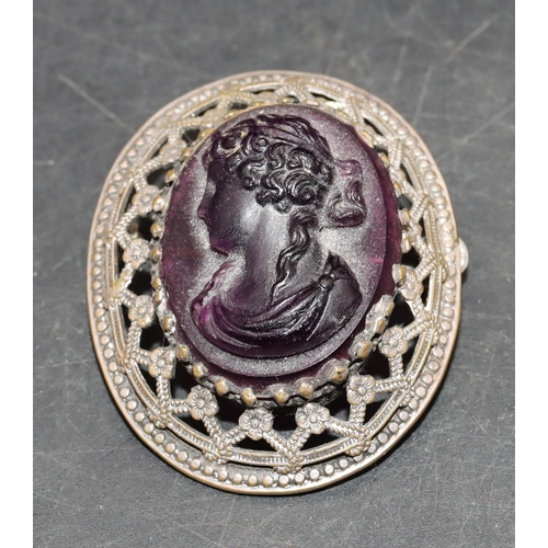 556 - An oval brooch set with carved purple oval hard stone with raised figurehead of a lady, 4.3cm high