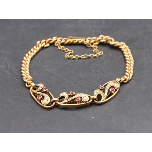 559 - A 15ct gold bracelet with 3 oval panels with raised red stones and half pearls, 9.1 grams gross