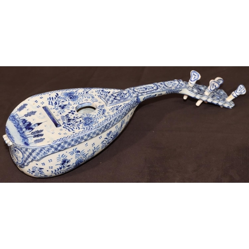 68 - A French Faience Delft style model of a mandolin on blue and white ground with building, floral, lea... 