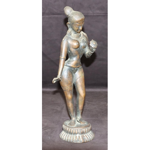 734 - An Eastern bronze figure of a female nude standing holding a petal, on round base, 38cm high