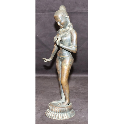 734 - An Eastern bronze figure of a female nude standing holding a petal, on round base, 38cm high