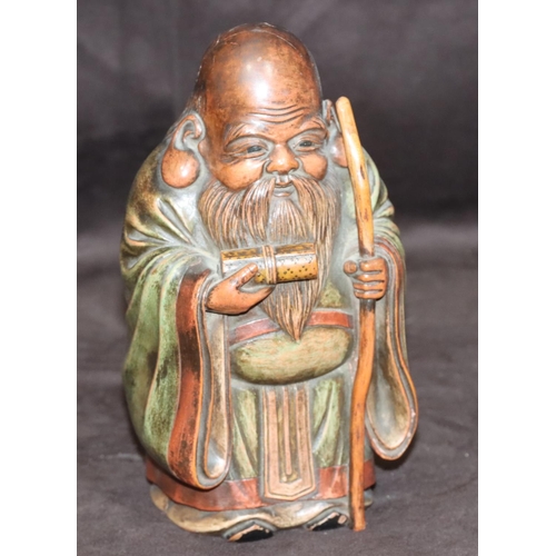 785 - An Oriental carved wooden figure of an elderly standing gentleman holding a staff with green cloak, ... 