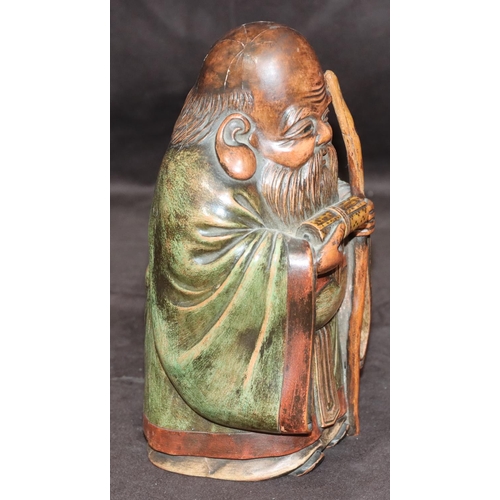 785 - An Oriental carved wooden figure of an elderly standing gentleman holding a staff with green cloak, ... 