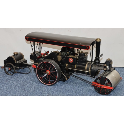 793 - A live model steam traction engine on black ground with separate trailer, gas fired, engine 50cm lon... 