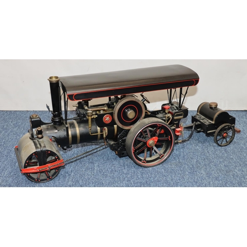 793 - A live model steam traction engine on black ground with separate trailer, gas fired, engine 50cm lon... 