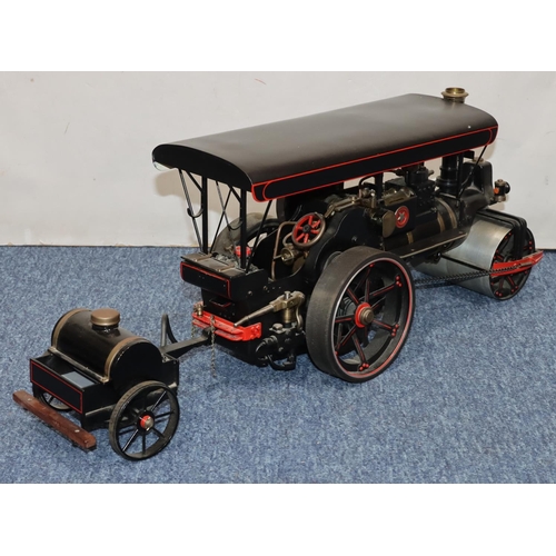 793 - A live model steam traction engine on black ground with separate trailer, gas fired, engine 50cm lon... 