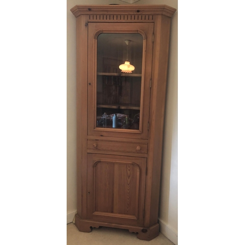 7170 - A pine corner cupboard with upper glazed panel door enclosing 2 shelves, small shallow drawer below ... 