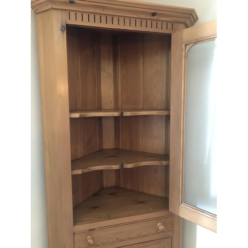 7170 - A pine corner cupboard with upper glazed panel door enclosing 2 shelves, small shallow drawer below ... 