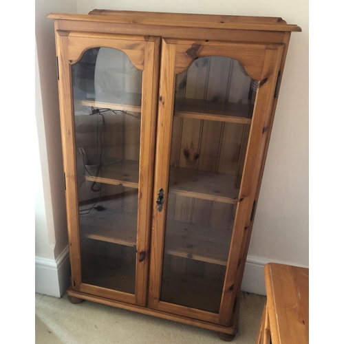 7175 - A pine bookcase with glazed double doors enclosing 3 interior pine shelves, 81cm wide, 32cm deep, 12... 