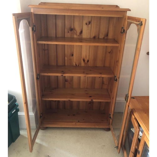 7175 - A pine bookcase with glazed double doors enclosing 3 interior pine shelves, 81cm wide, 32cm deep, 12... 