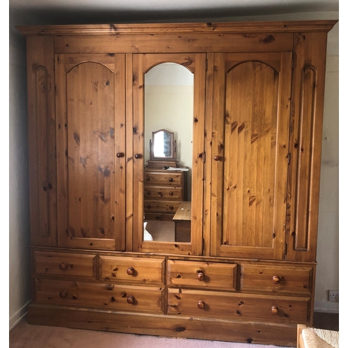 7235 - A pine triple cupboard with central mirrored door flanked by pine doors enclosing interior hanging a... 