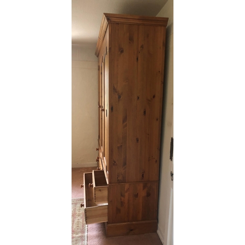 7235 - A pine triple cupboard with central mirrored door flanked by pine doors enclosing interior hanging a... 