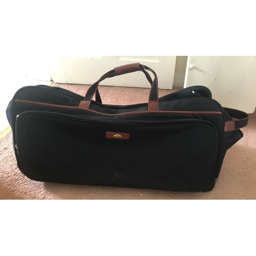 7238 - A large black canvas Samsonite holdall bag on 2 wheels, brown leather detail, carrying handles with ... 