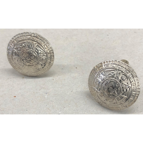 7252 - A pair of circular silver coloured metal Aztec patterned cufflinks, 2cm diameter