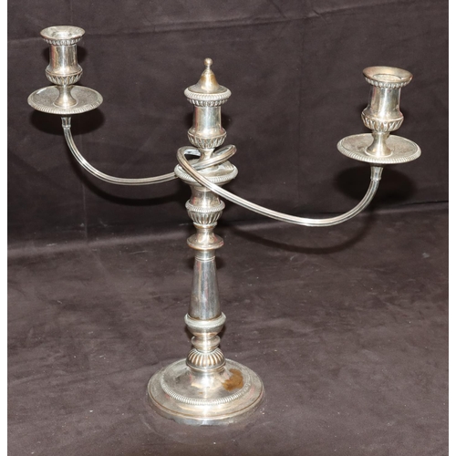 299 - A silver plated 2-branch candelabra with scroll shaped arms on turned stems with round sweeping base... 