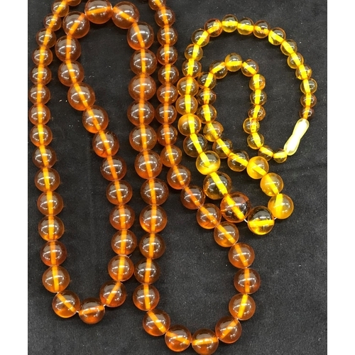 8039 - 2 amber coloured necklaces, approx. 84cm and 44cm long overall.