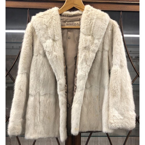 8285 - A short cream fur coat with 2 pockets, Howells of Cardiff label, 65cm long overall (no size, approx.... 