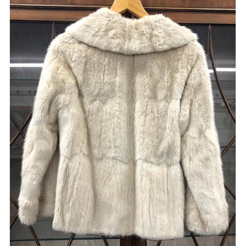 8285 - A short cream fur coat with 2 pockets, Howells of Cardiff label, 65cm long overall (no size, approx.... 