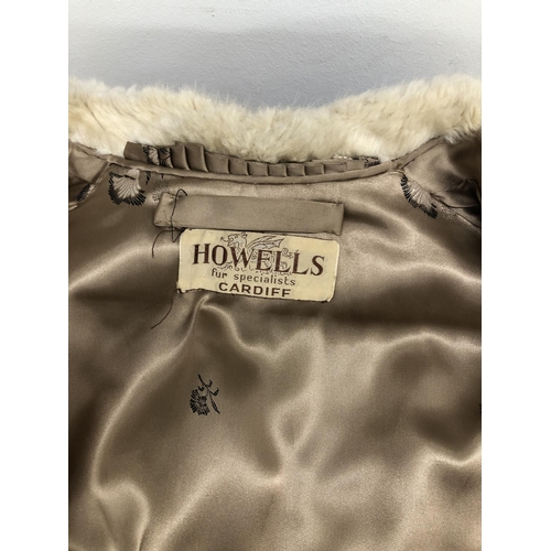 8285 - A short cream fur coat with 2 pockets, Howells of Cardiff label, 65cm long overall (no size, approx.... 