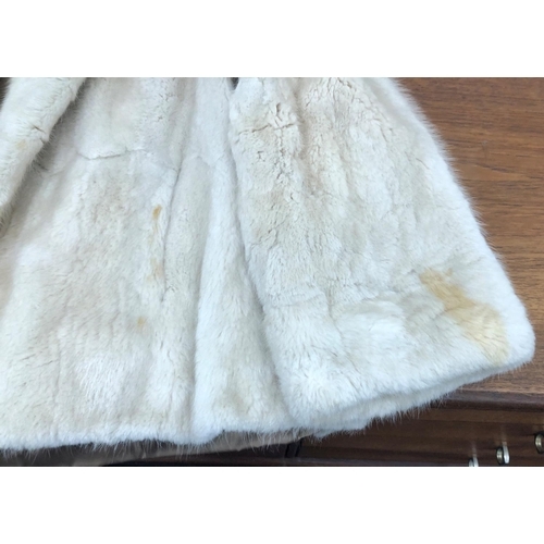 8285 - A short cream fur coat with 2 pockets, Howells of Cardiff label, 65cm long overall (no size, approx.... 