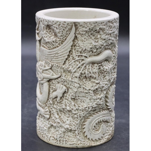 110 - An Oriental white glazed brush pot with raised dragon and Phoenix decoration on white ground, 15cm h... 