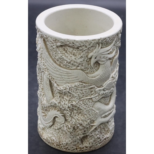 110 - An Oriental white glazed brush pot with raised dragon and Phoenix decoration on white ground, 15cm h... 