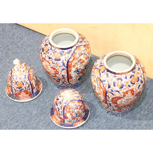 124 - A pair of Imari round bulbous lidded ginger jars on white, red and blue ground with allover floral, ... 