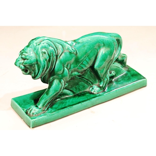 131 - A large green glazed model of a prowling lion on rectangular shaped base, 45cm long, 25cm high