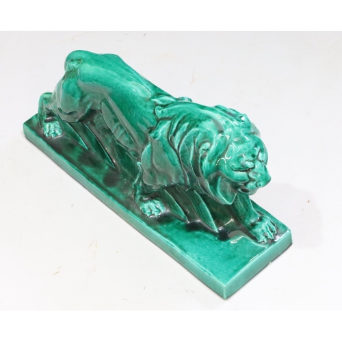 131 - A large green glazed model of a prowling lion on rectangular shaped base, 45cm long, 25cm high