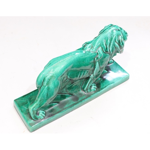 131 - A large green glazed model of a prowling lion on rectangular shaped base, 45cm long, 25cm high