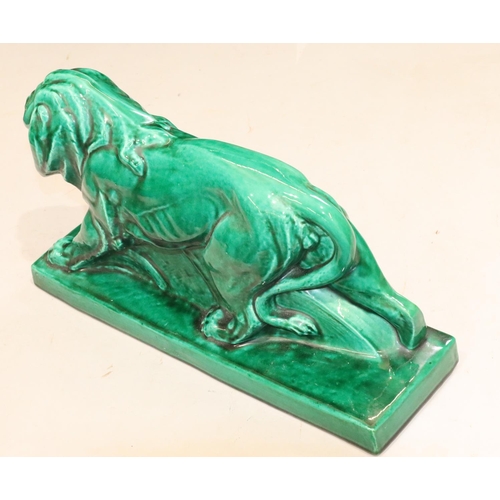 131 - A large green glazed model of a prowling lion on rectangular shaped base, 45cm long, 25cm high