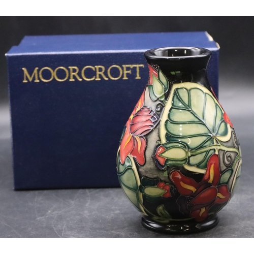 159 - A modern Moorcroft small round bulbous thin necked vase on dark blue ground with multi-coloured flor... 