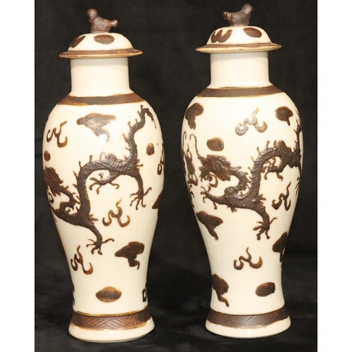 172 - A pair of Chinese round bulbous thin necked lidded vases on white ground with raised brown, dragon a... 