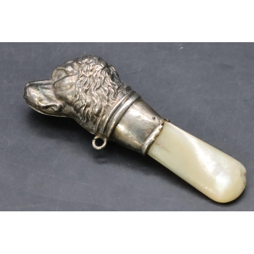 245 - A child's silver and Mother of Pearl rattle in the form of a dog's head (bell missing and teeth mark... 