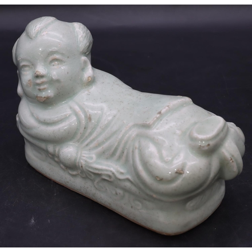 51 - An Oriental glazed earthenware pillow in the form of a child on pale green ground, 20cm long