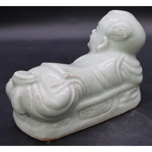 51 - An Oriental glazed earthenware pillow in the form of a child on pale green ground, 20cm long